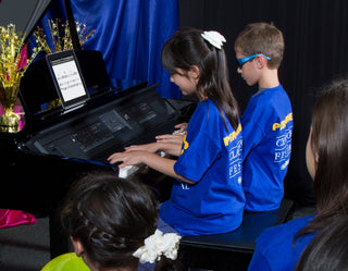 Two children sitting at Yamaha Clavinova together playing a duet