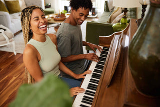 Happy healthy couple playing piano together in living room