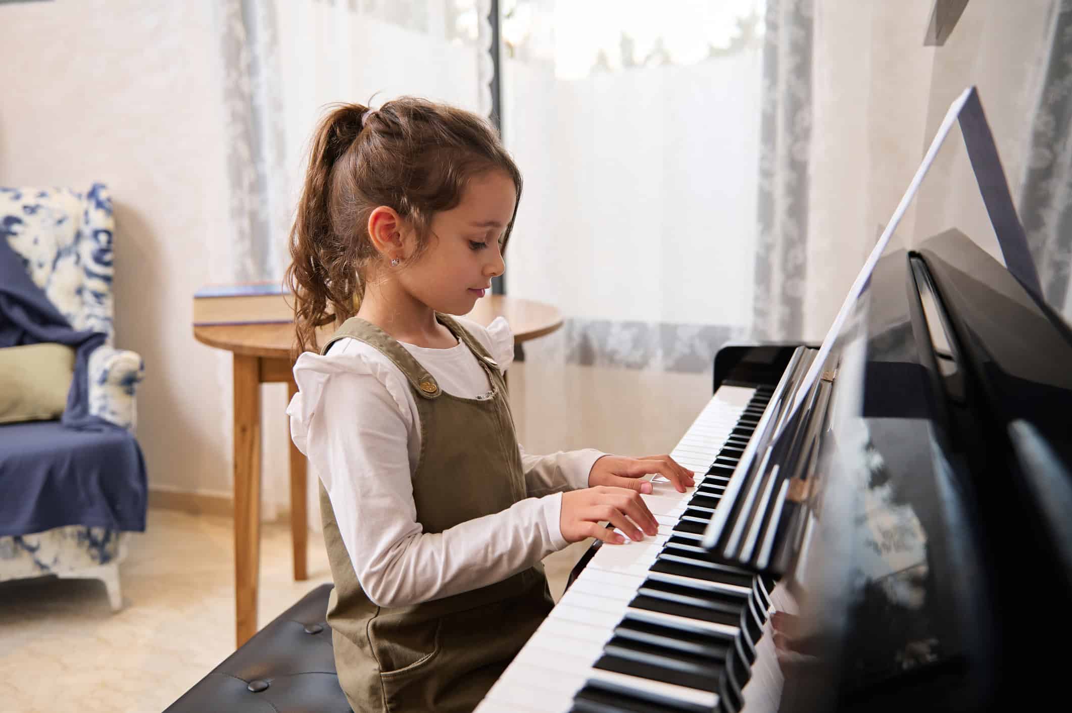 Young student at the piano practicing after piano teacher helps her find a way to stay motivated to play and to enjoy it